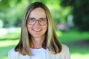 Portraitfoto Frau Dr. Hietel-Weniger, Frau mit braunen Haaren, Brille, weißer Bluse und grauem Jackett.