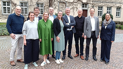 Gruppenfoto mit in die Kamera lächelnden Frauen und Männern im Innenhof eines historischen Gebäudes.
